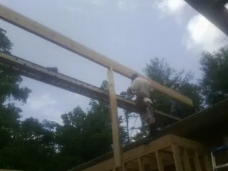 Carpenter setting a ridge beam over a new addition frame — Ice Dam Removal by Roofing Brothers in Imlay City
