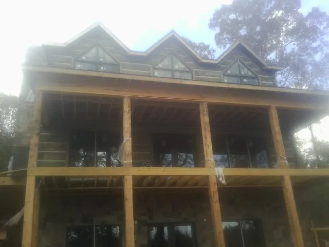 Dormers and porch framing on a large log home under construction — Roof Coating work by our crew in Imlay City