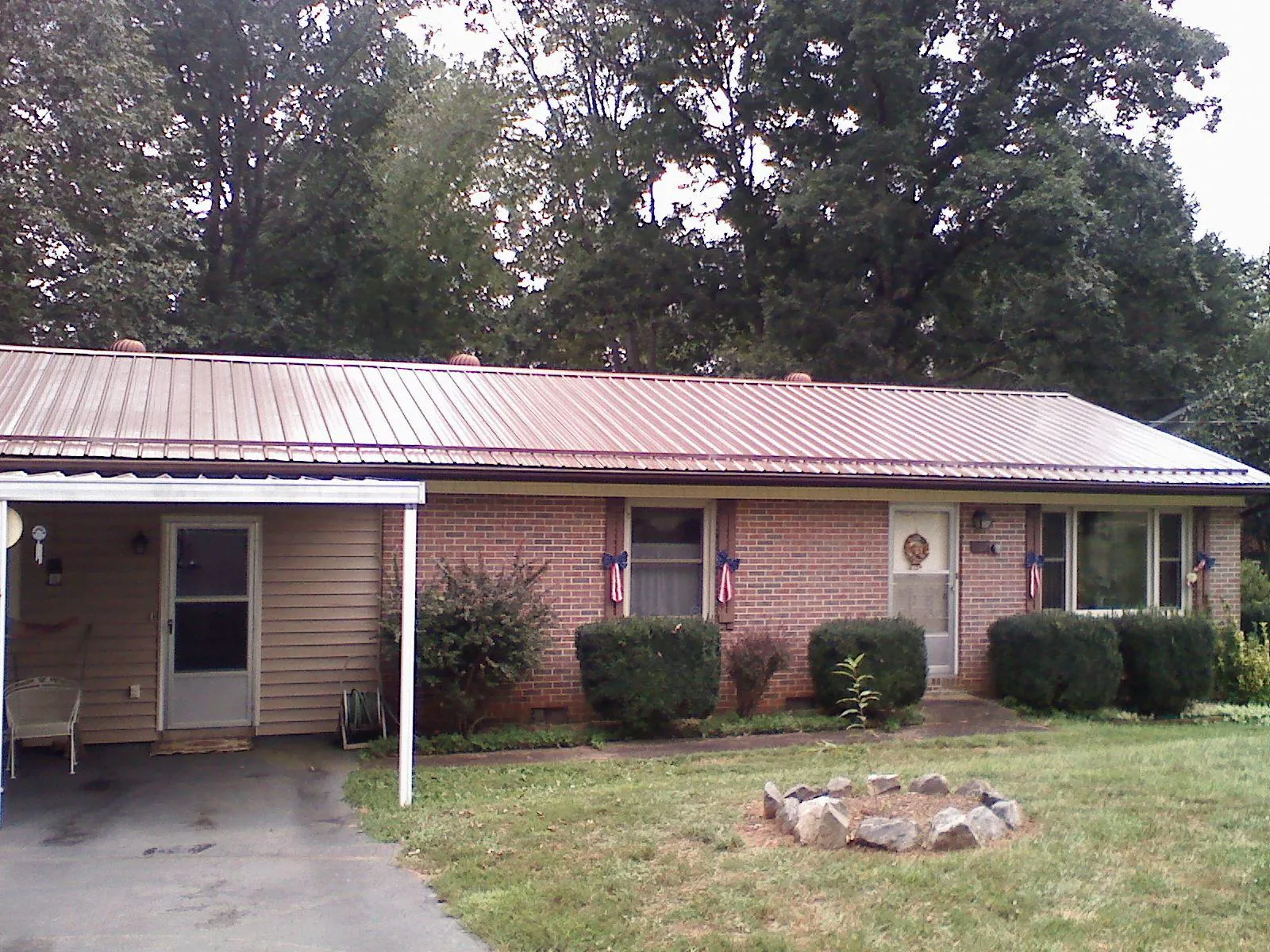 Bronze metal roof and carport on a brick ranch home — Roof Repair work by our crew in Imlay City