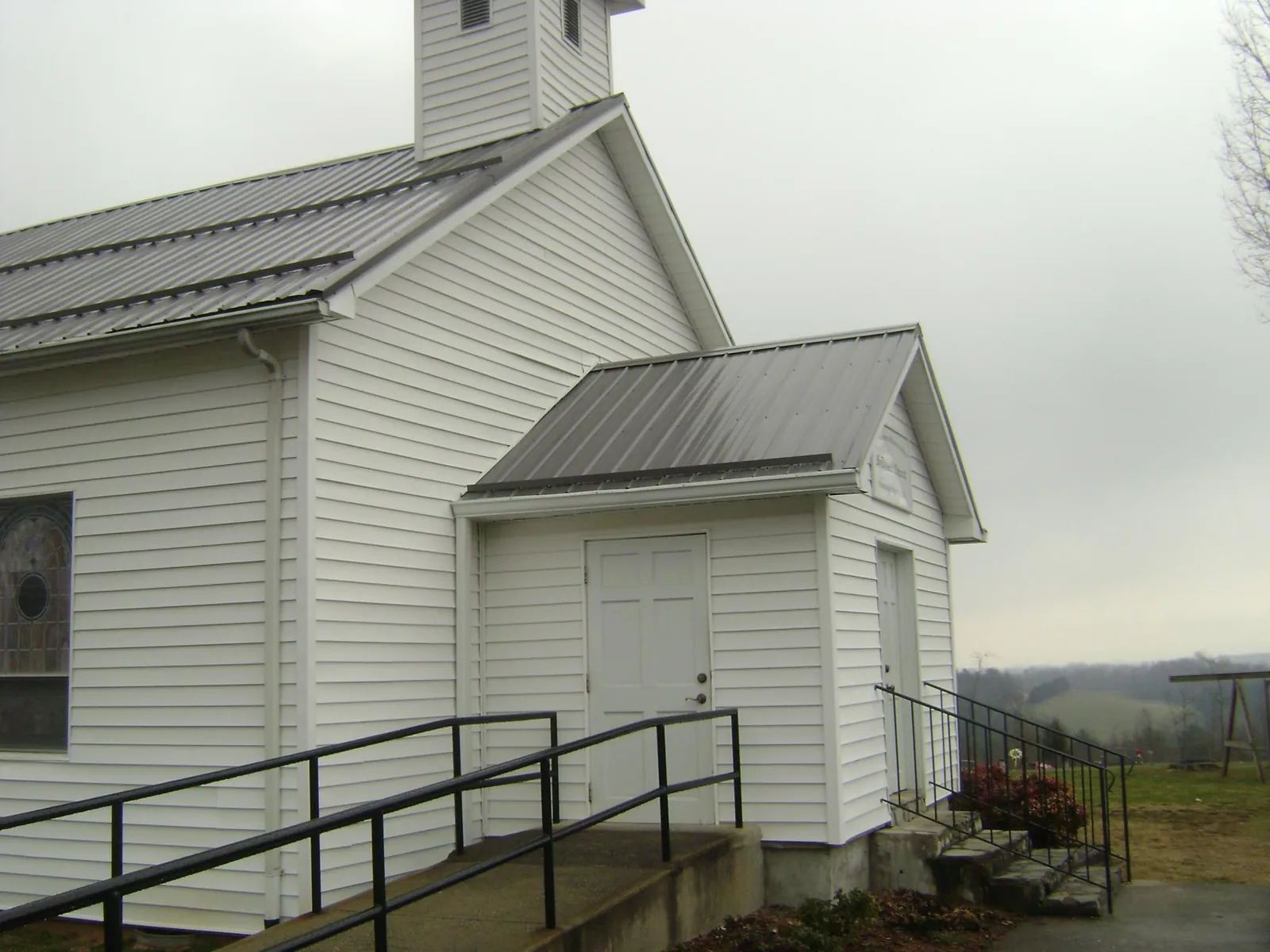 Gray metal roof on a white clapboard church with a steeple in Imlay City
